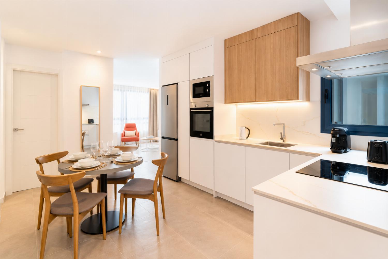Modern open-plan kitchen and dining area with warm wooden cabinetry and a stylish table setting.