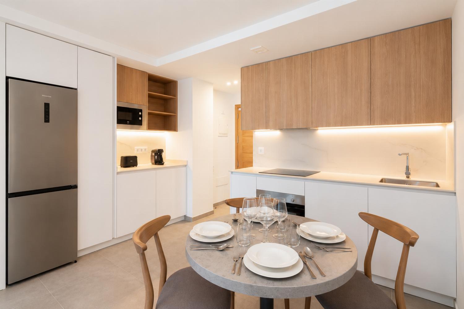 Modern open-plan kitchen and dining area with warm wooden cabinetry and a stylish table setting.