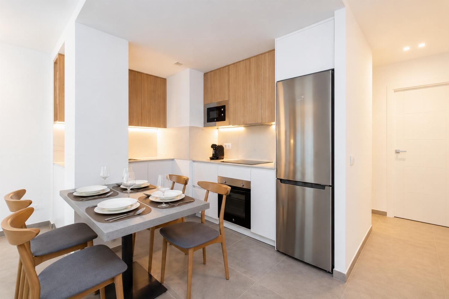 Modern open-plan kitchen and dining area with warm wooden cabinetry and a stylish table setting.