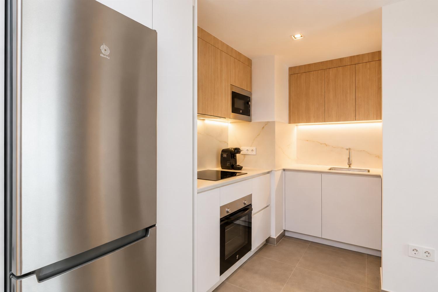 Modern open-plan kitchen and dining area with warm wooden cabinetry and a stylish table setting.