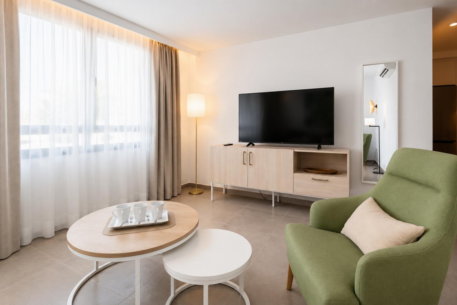 Open-plan living room with sofa, kitchen, A/C, WiFi and TV