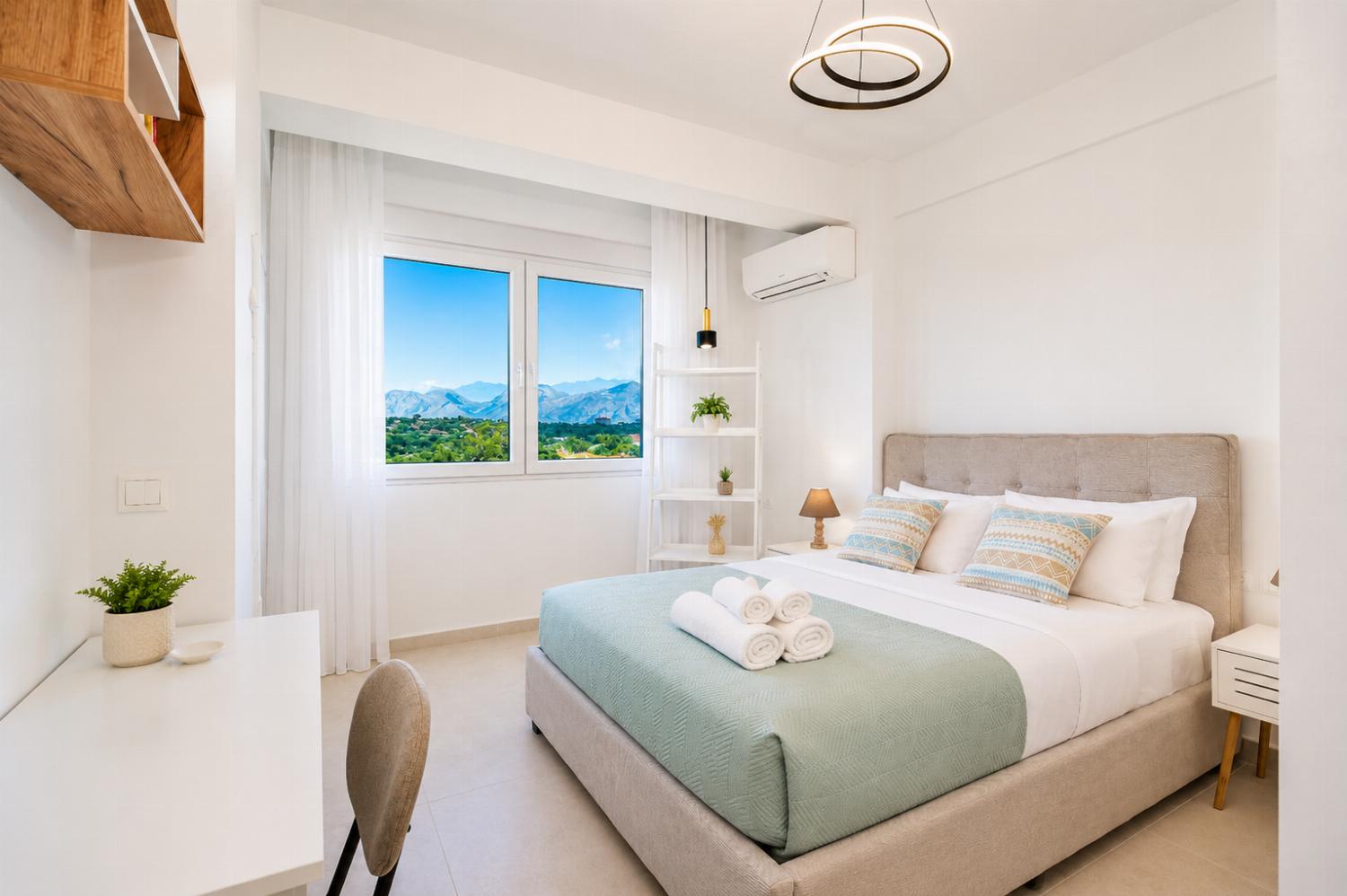 Bright double bedroom with soft green accents, modern decor, and beautiful mountain views.