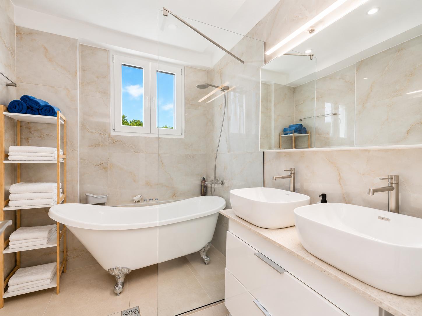 Elegant bathroom with a freestanding bathtub, double vanity, and bright marble-style finishes.