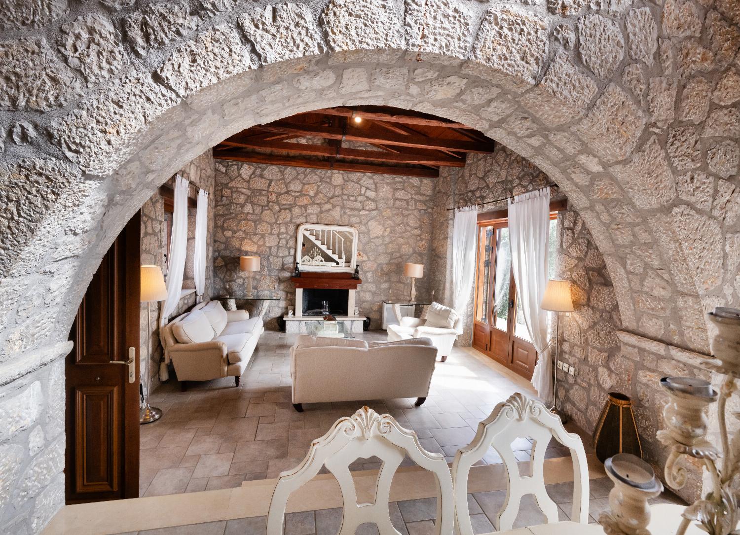 Stone archway opening into a rustic living room with a fireplace.