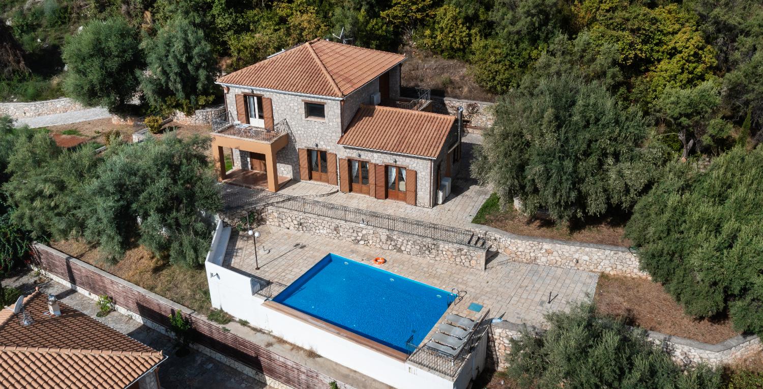 Aerial view of a stone villa with a private pool and terraced patios.