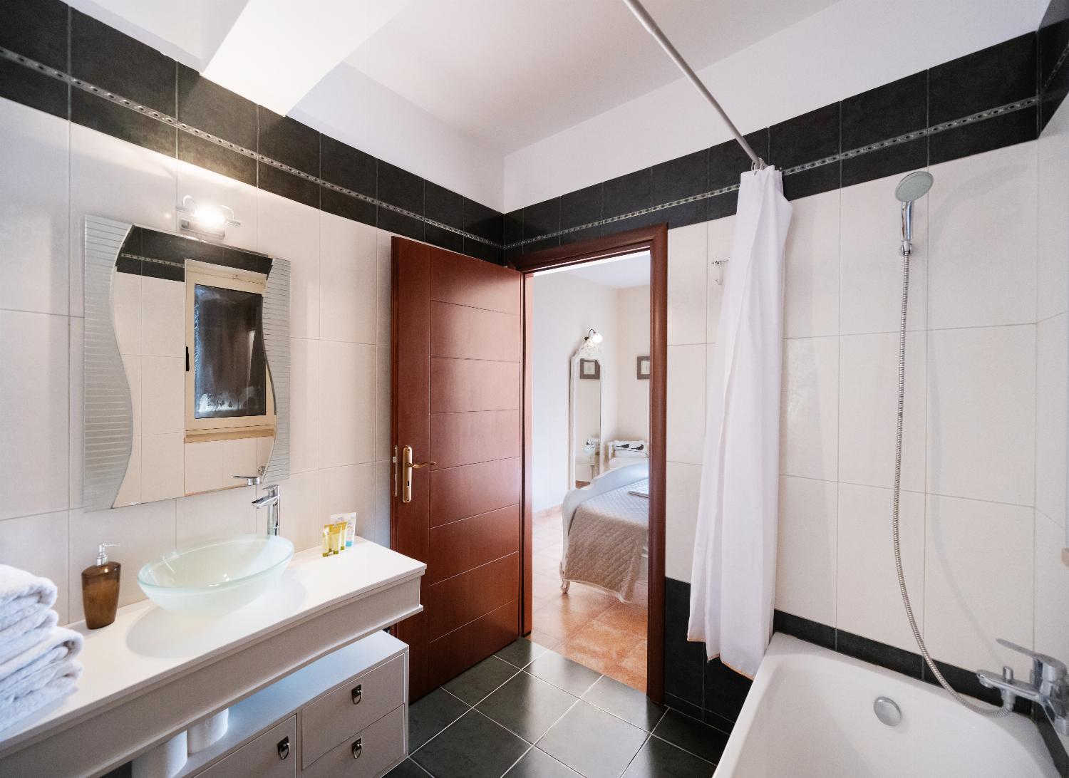 Modern bathroom with a black and white tiled design, bathtub, and glass vessel sink.