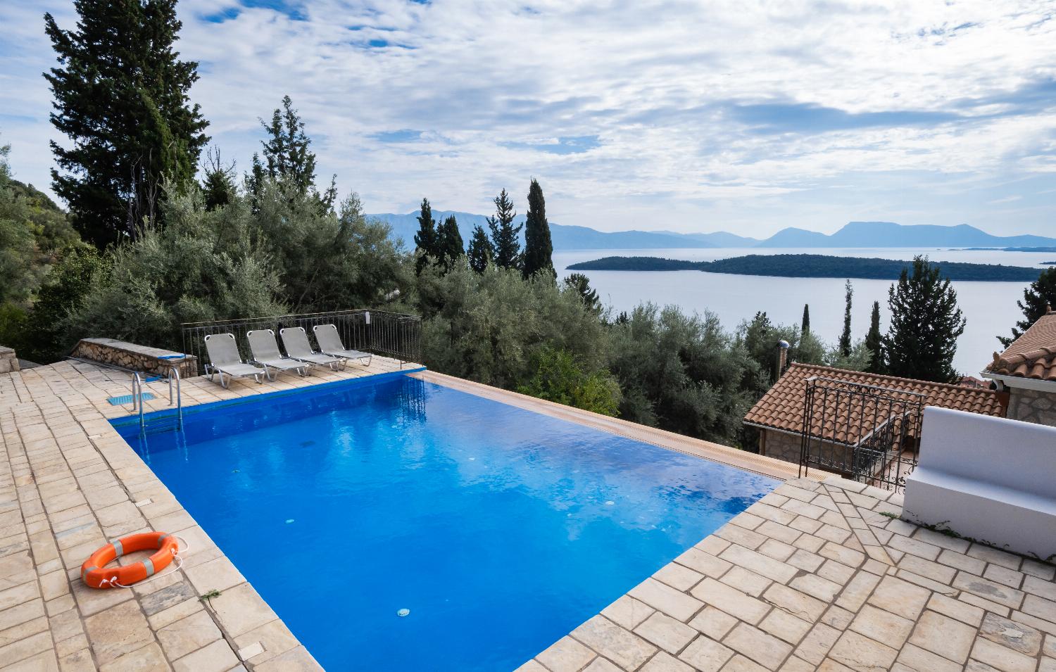 Infinity swimming pool with sun loungers overlooking a scenic island bay.