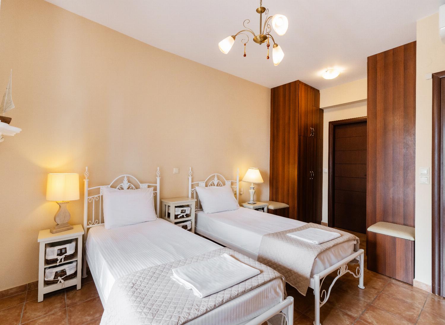 Twin bedroom featuring ornate white metal bed frames and dark wood wardrobes.