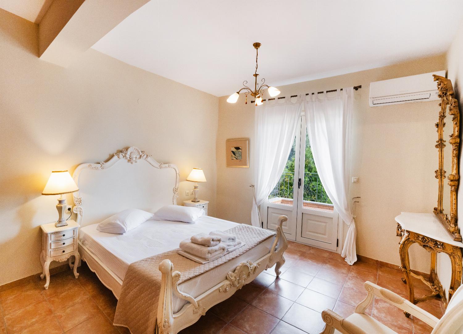 Elegant bedroom featuring an ornate white bed frame and balcony doors.