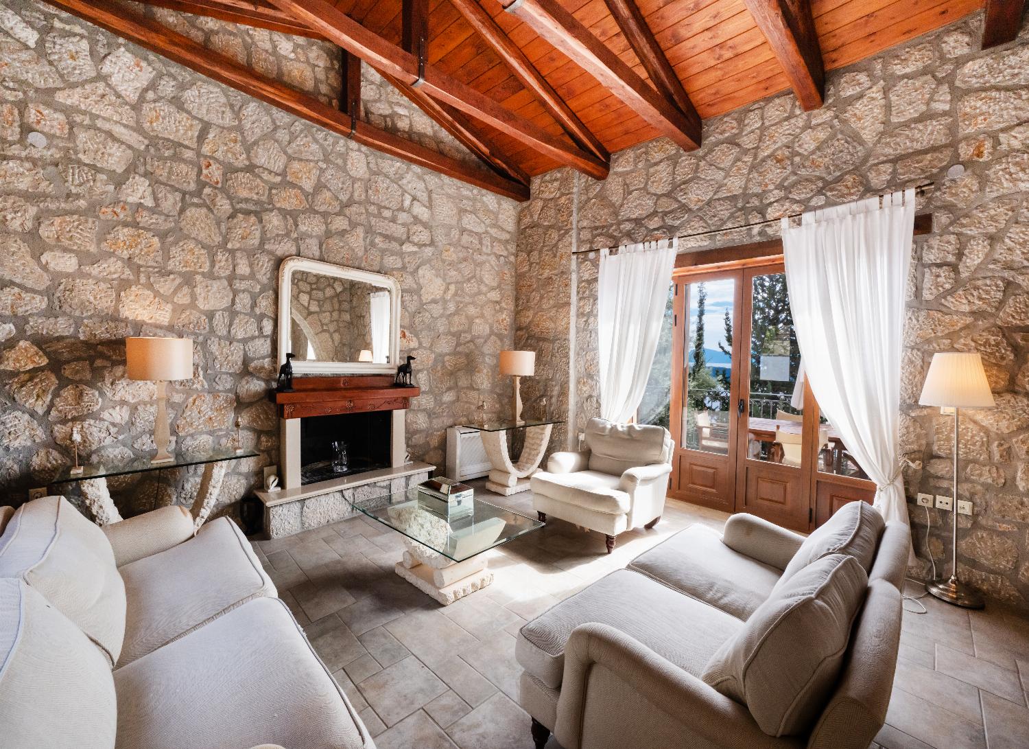 Stone living room with a vaulted wooden ceiling, fireplace, and cozy seating.