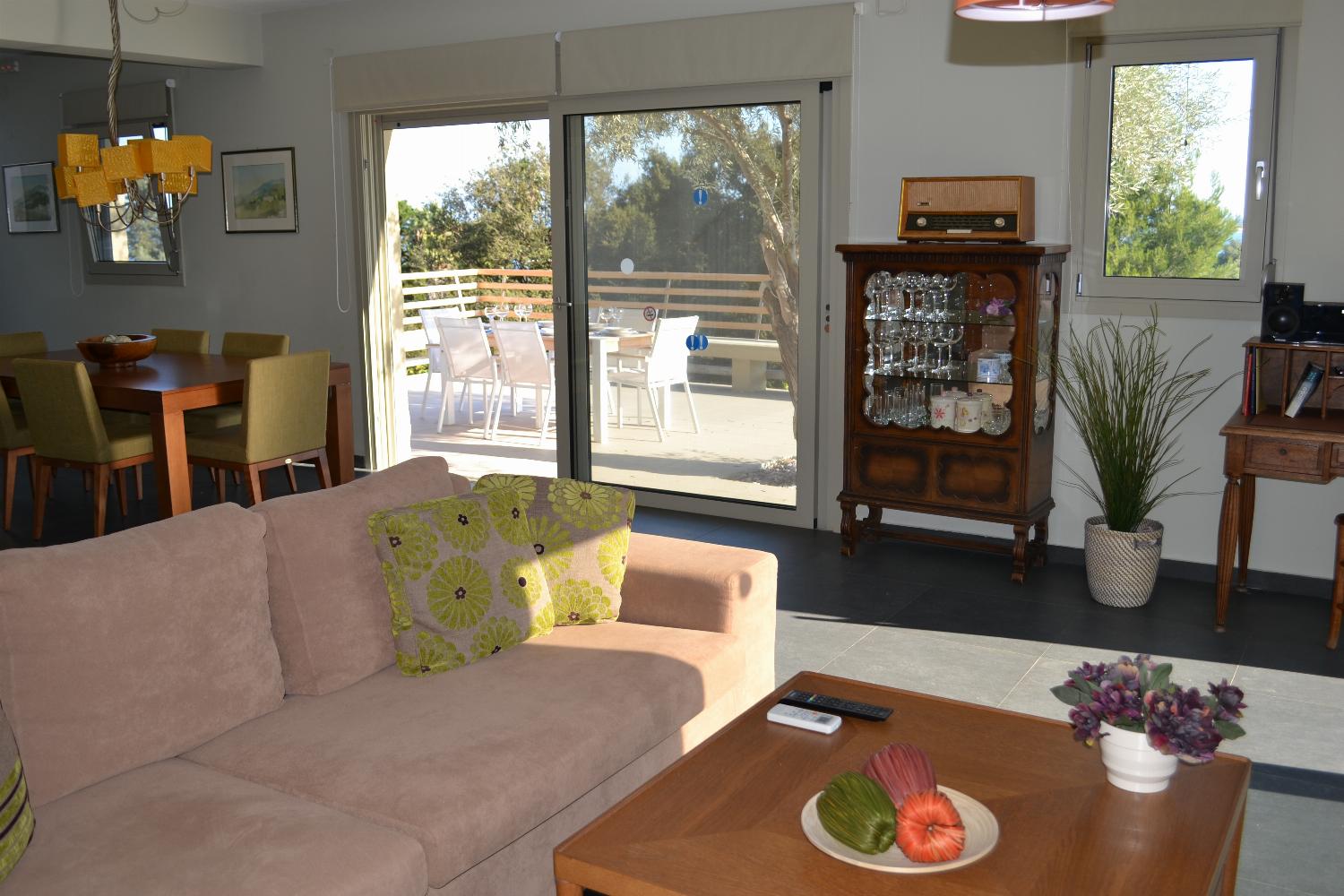 A cozy living area features a beige sectional sofa facing a fireplace and a wall-mounted television, with large sliding glass doors opening directly onto the outdoor pool patio.