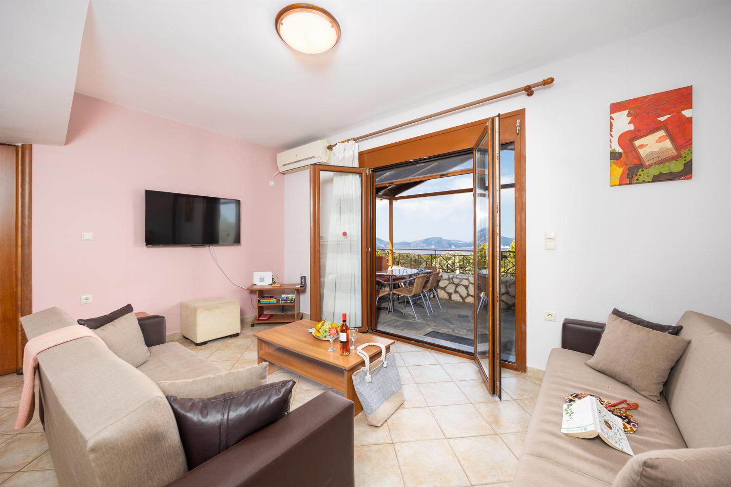 Open-plan living room with sofas, dining area, kitchen, ornamental fireplace, A/C, WiFi internet, and satellite TV