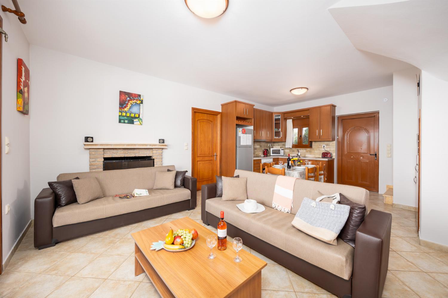 Open-plan living room with sofas, dining area, kitchen, ornamental fireplace, A/C, WiFi internet, and satellite TV