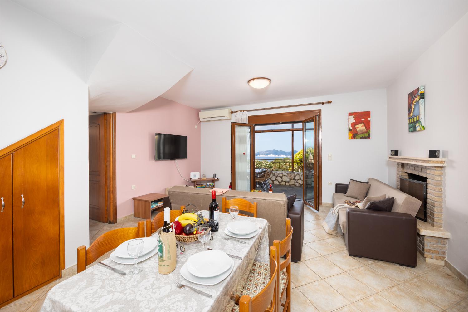 Open-plan living room with sofas, dining area, kitchen, ornamental fireplace, A/C, WiFi internet, and satellite TV