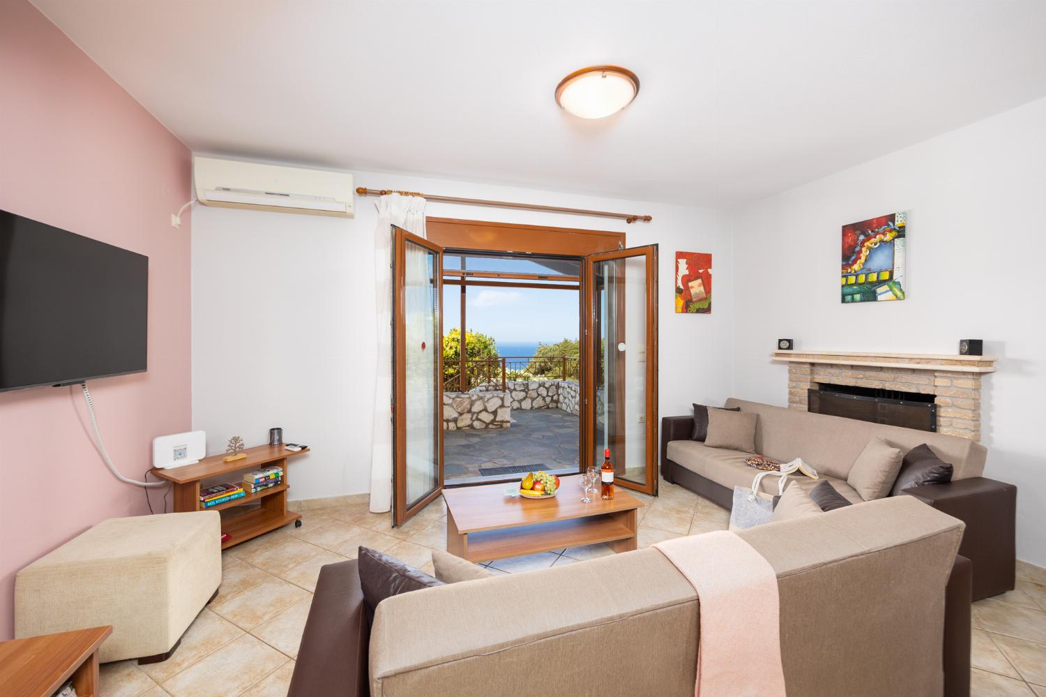 Open-plan living room with sofas, dining area, kitchen, ornamental fireplace, A/C, WiFi internet, and satellite TV